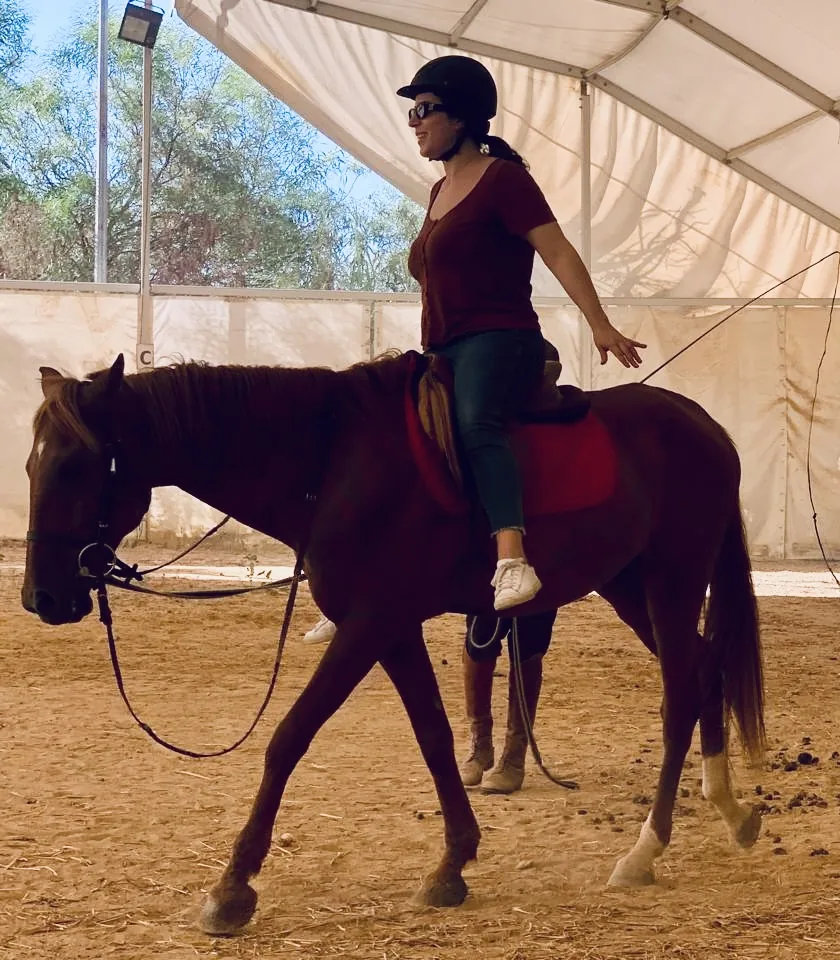 Riding a chestnut horse in the arena